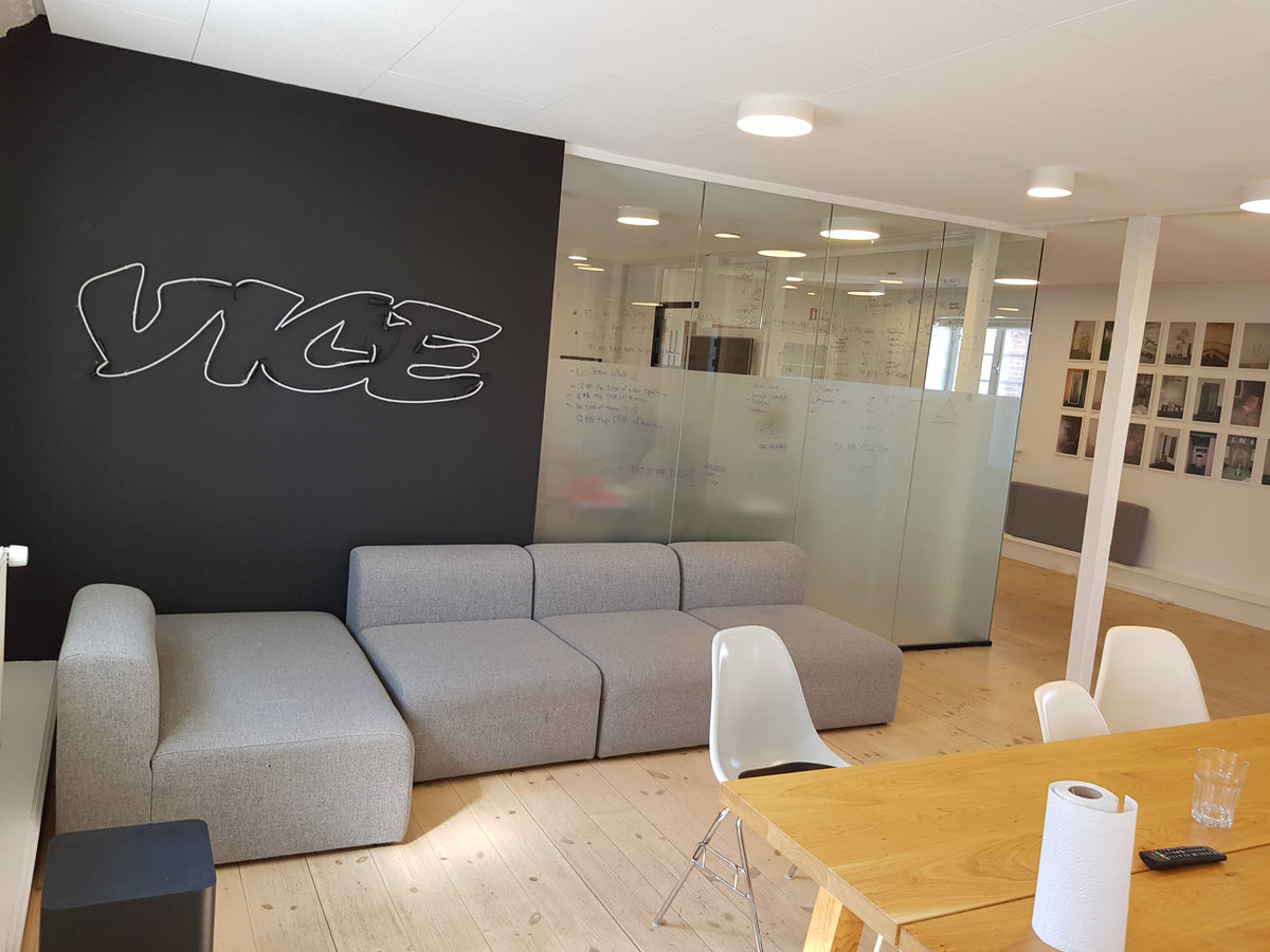 Hvidt VICE-logo i neon på en mørk væg i et mødeområde