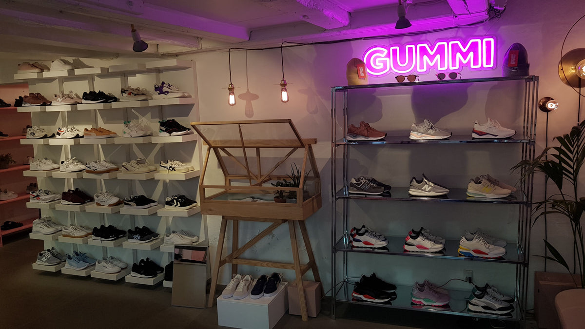 Pink neonskilt med GUMMI over sneakerhylder i en butik