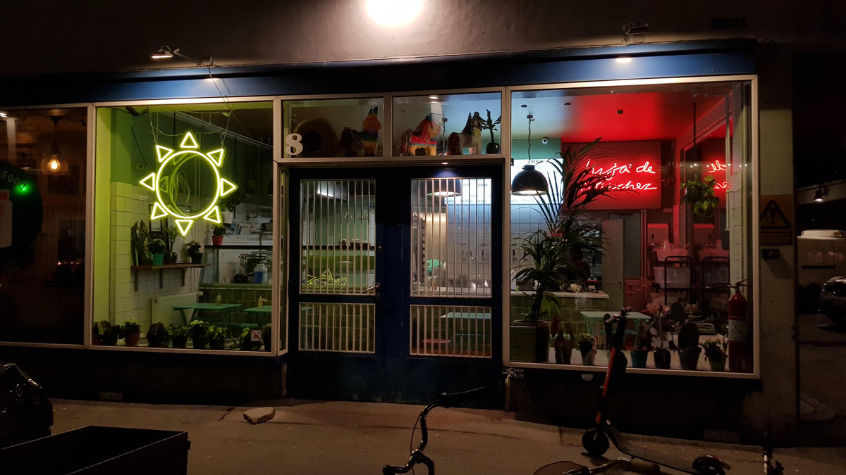 Gul neonsol og rød neontekst i vinduerne på en café om aftenen