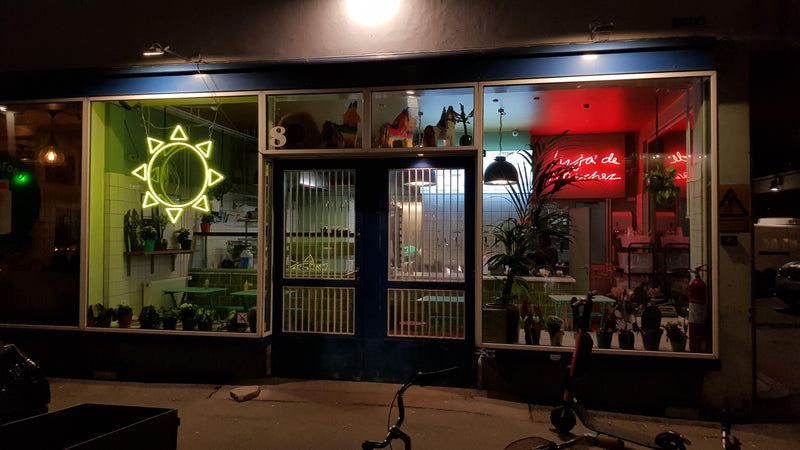 Gul neonsol og rød neontekst i vinduerne på en café om aftenen
