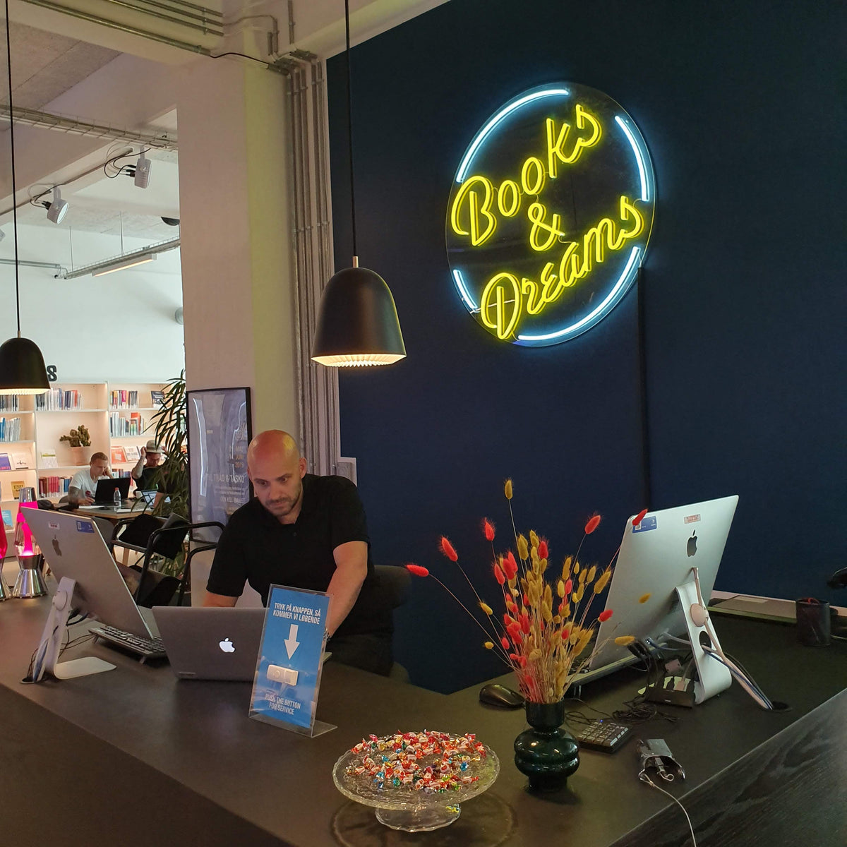Gult og blåt neonskilt med Books &amp; Dreams bag en reception
