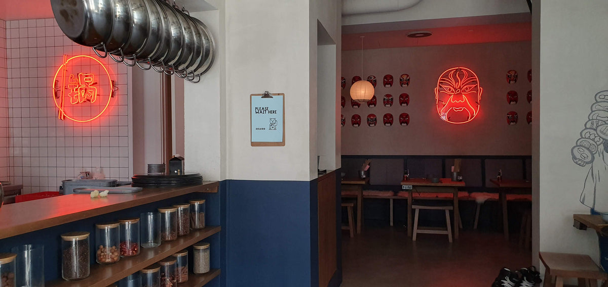 Røde neonskilte med kinesisk tegn og en operamaske i en restaurant