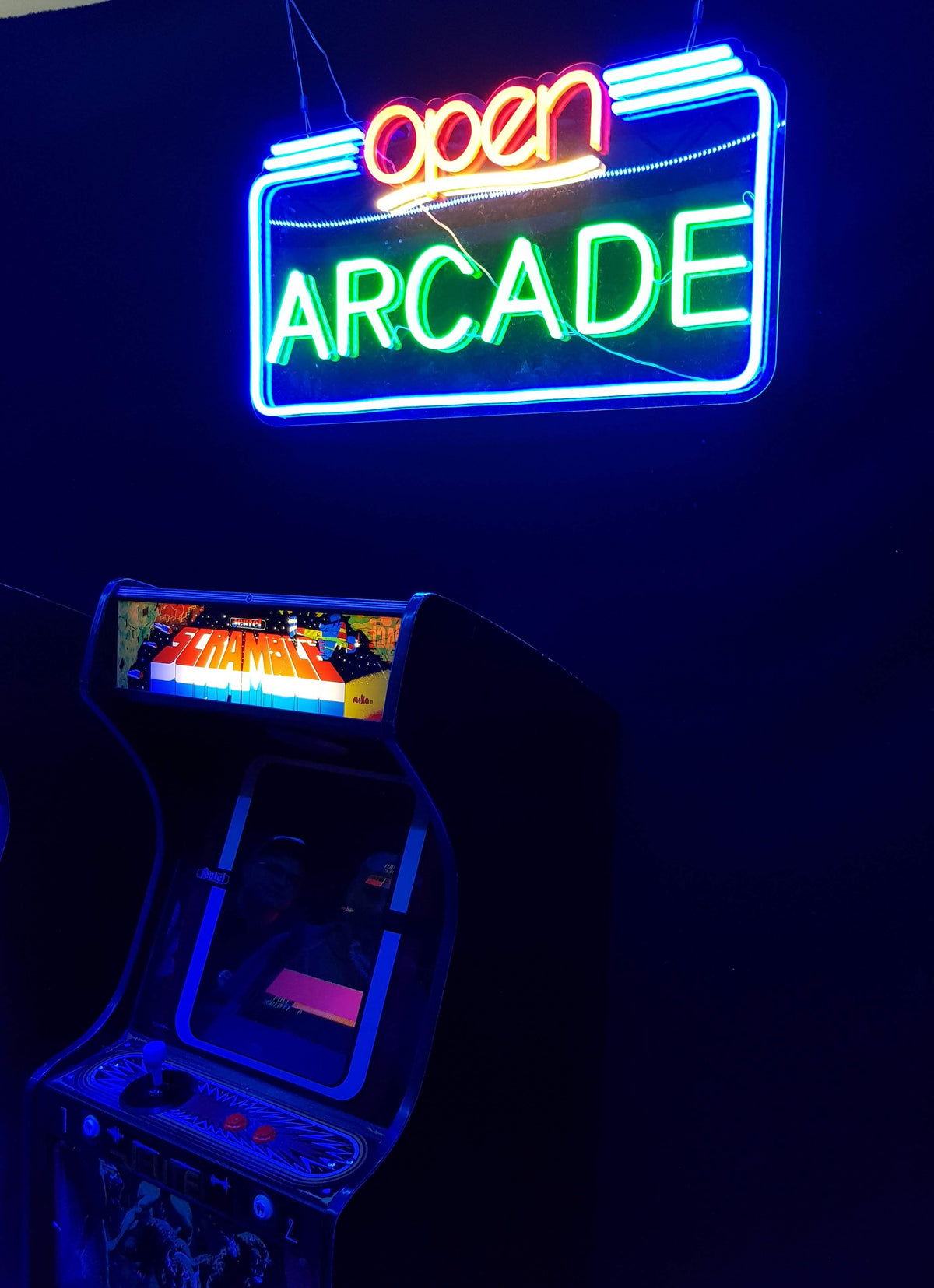 Neonskilt med OPEN ARCADE over en arkademaskine