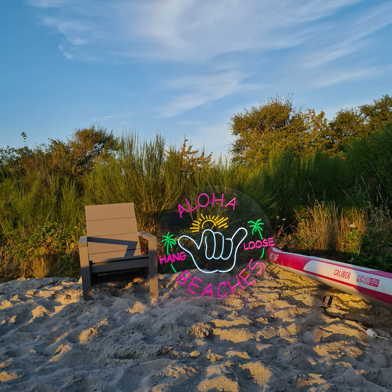 Neonskilt med ALOHA BEACHES og en hang loose-hånd på en strand