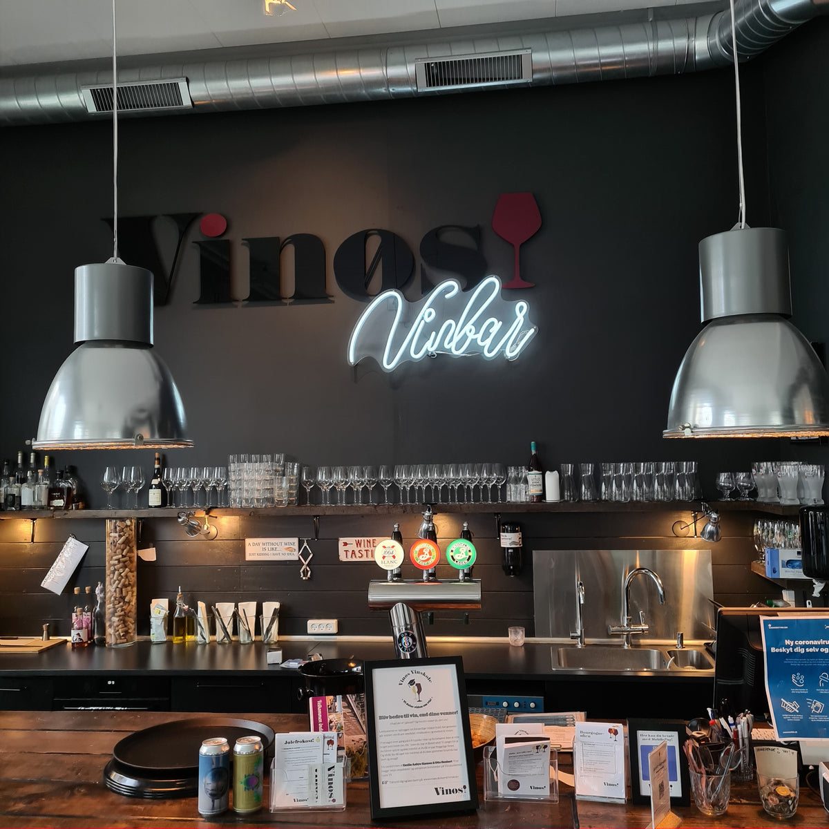 Hvidt neonskilt med teksten Vinbar over baren hos Vinøs