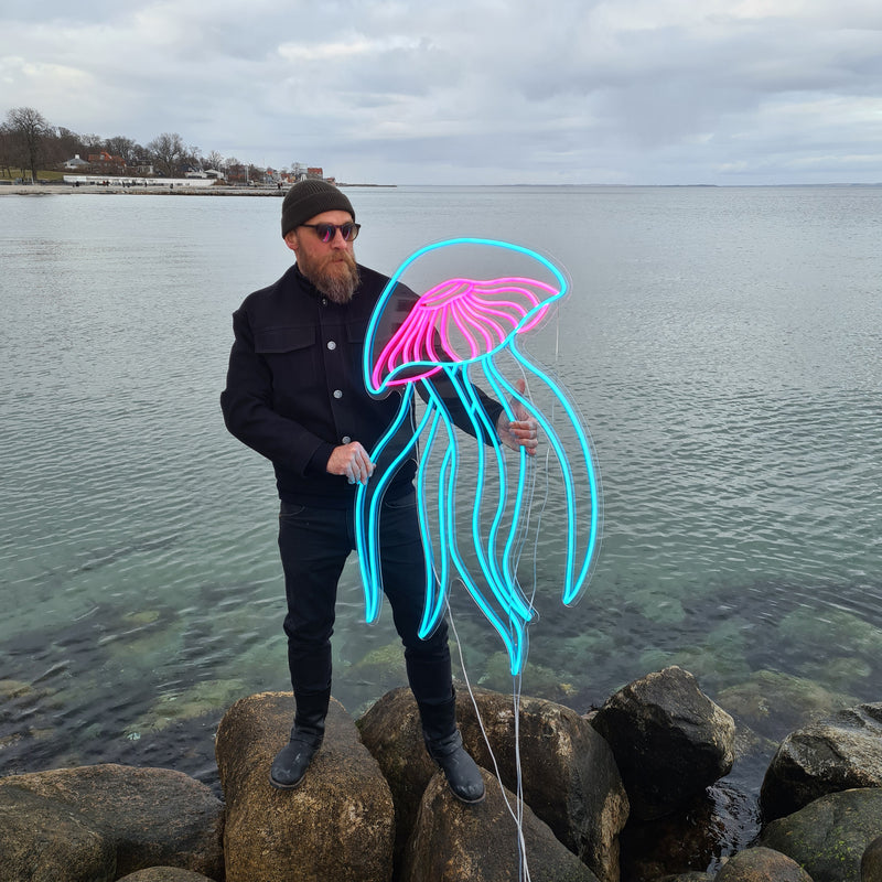 Neonvandmand i turkis og pink ved vandet