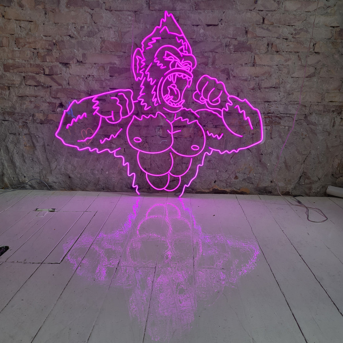 Stor pink neongorilla på en murstensvæg