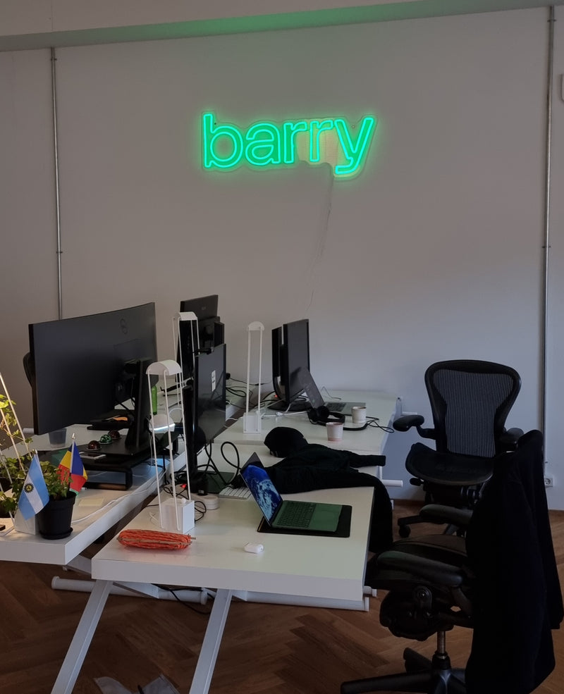 Grønt neonlogo med barry over skriveborde på et kontor