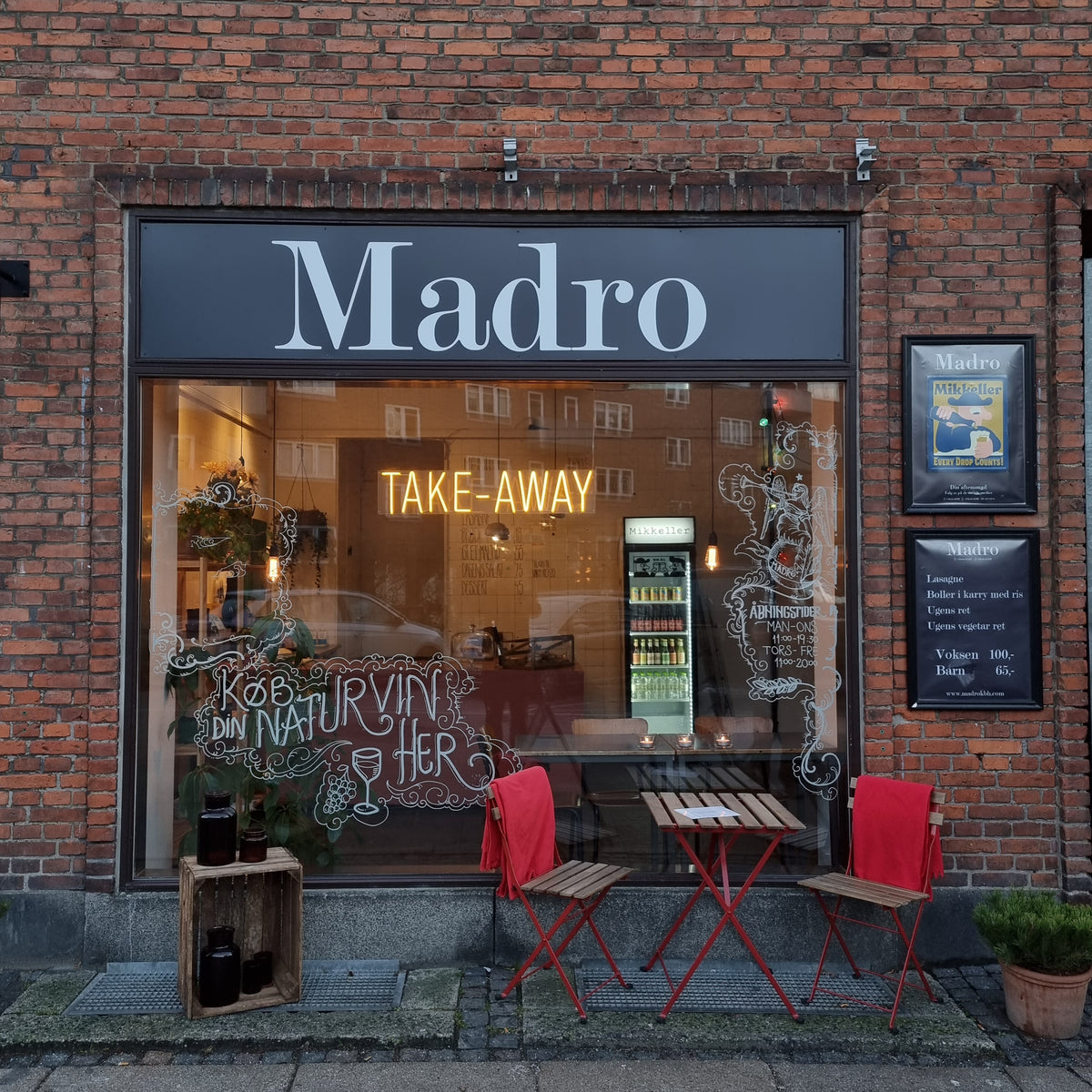 Gult neonskilt med TAKE-AWAY i vinduet hos Madro