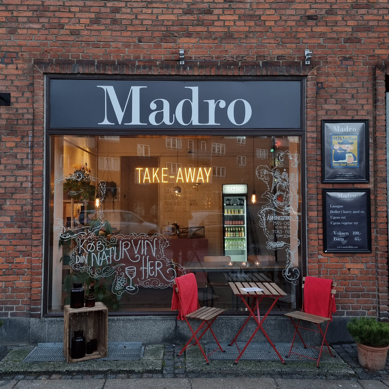 Gult neonskilt med TAKE-AWAY i vinduet hos Madro