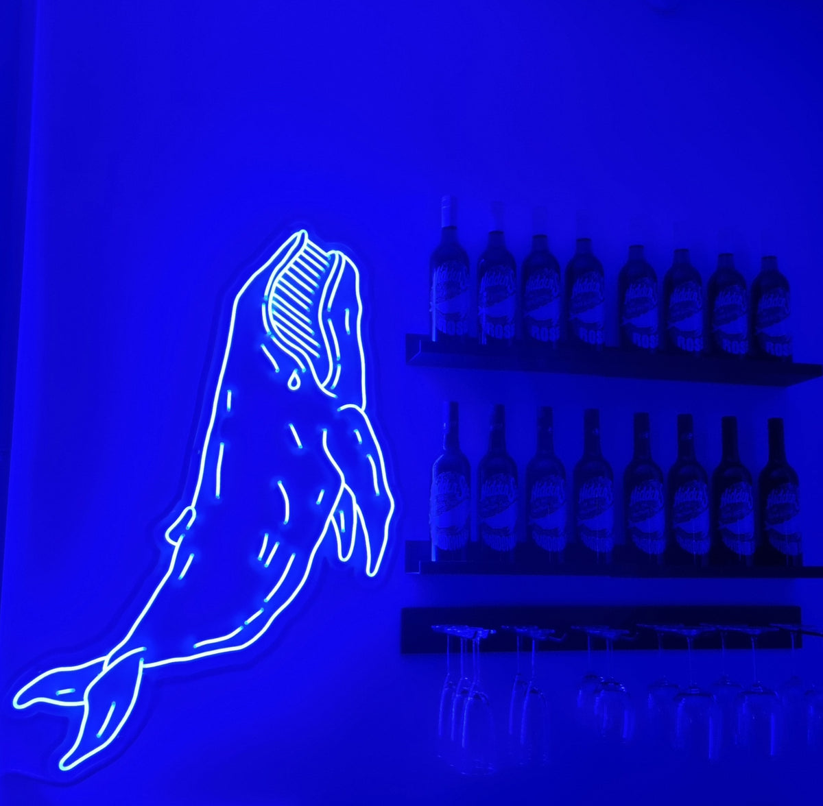 Blå neonhval ved siden af flaskehylder i en bar