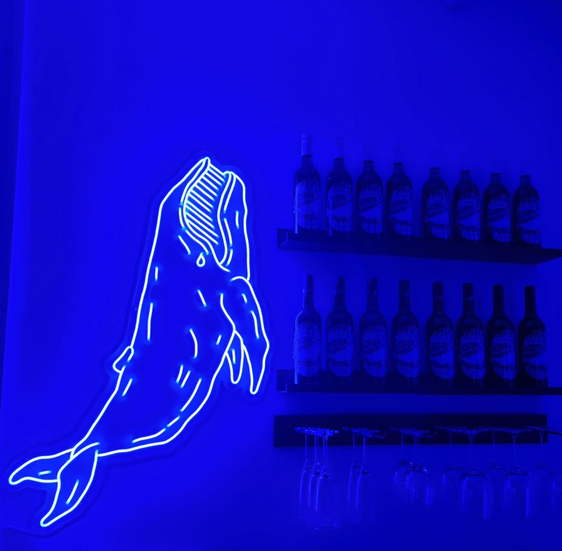Blå neonhval ved siden af flaskehylder i en bar