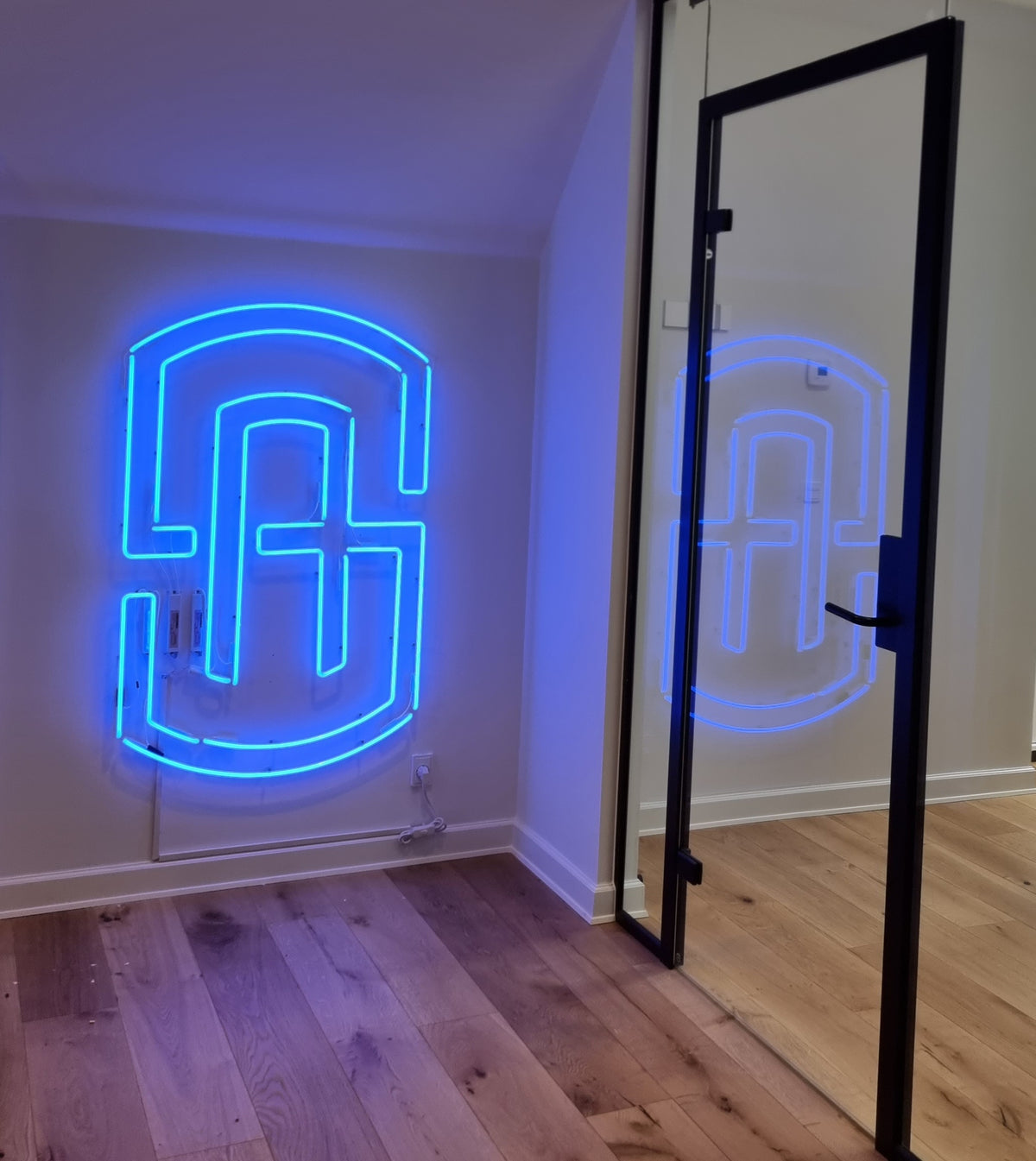 Blåt neonlogo på væggen ved en glasdør på et kontor