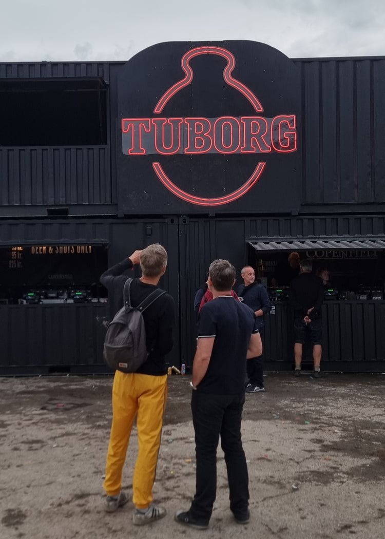 Rødt neonlogo for Tuborg på en containerbar til en festival