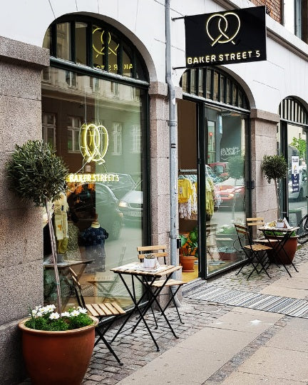 Butiksfacade for Baker Street's med kringlelogoet i gul LED-neon i vinduet